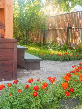 Tuğladan bir kır evinde küçük ahşap bir veranda ve güneşli bir yaz gününde ağaçların ve çimlerin arkasında yeni bir ahşap çit..