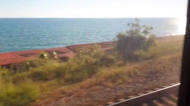 4k video, deniz kıyısı boyunca tren penceresinden bir manzara, gün batımında birinci şahıs tren yolculuğu.