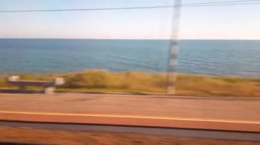 4k video, deniz kıyısı boyunca tren penceresinden bir manzara, gün batımında birinci şahıs tren yolculuğu.