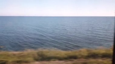 4k video, deniz kıyısı boyunca tren penceresinden bir manzara, gün batımında birinci şahıs tren yolculuğu.