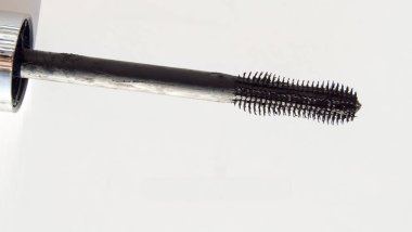 Beyaz arkaplanda izole edilmiş siyah bir rimel fırçasının yakın çekimi.