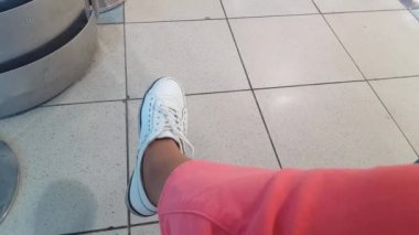4k, Women's legs in pink trousers and white shoes, carefree rocking, sitting in the airport waiting room
