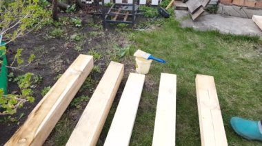 4k video, bir kadının eli koruyucu cila uyguluyor arka bahçedeki çimlerin üzerinde uzanan yeni keresteler için..