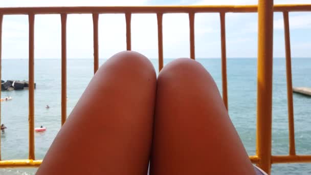 4K视频 一个年轻女子躺在海边和日光浴的躺椅上的观点 暑假期间 在海滩上 女人在躺椅上的腿放松一下 享受一下 — 图库视频影像