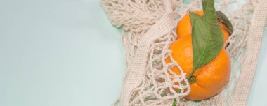 İp torbasında mandalina bulunan mavi afiş. Sağlıklı yaşam tarzı, üst görünüm, sıfır atık.