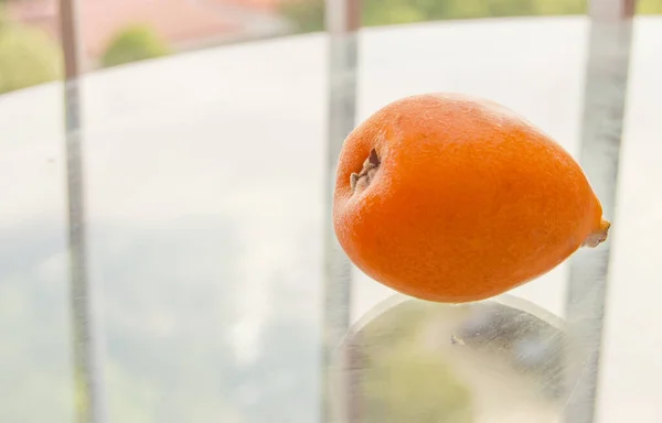 Medlar fruit on a transparent glass table on the balcony, close-up, outdoor — Stock Photo, Image