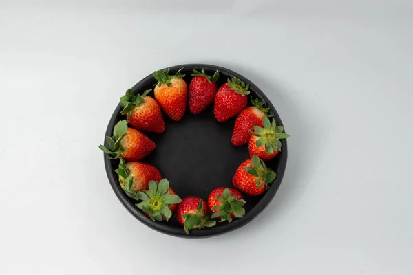 Strawberries on blueberries in handmade clay dish and white background