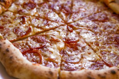 İştah açıcı pizza dilimleri masada, bir el sosa bir dilim pizza batırıyor. Bol salamlı ve peynirli pizza. Parmak yiyeceği.. 