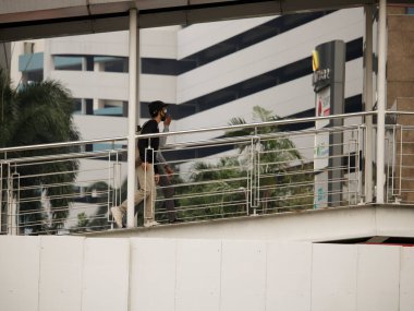 Jakarta, Indonesia - August 20, 2022: Morning commuters walk uphill from the TransJakarta bus terminal in Jakarta's business district