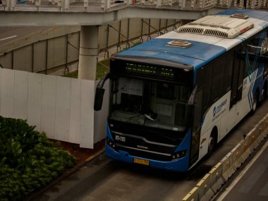 Jakarta, Indonesia - August 20, 2022: Trans Jakarta buses pass the bus stop on Jalan Sudirman, South Jakarta, Indonesia to reduce congestion