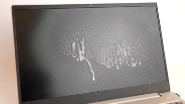 Adam dizüstü bilgisayarı deterjanla temizliyor. PC bakım kavramı