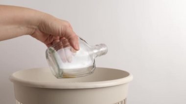 The glass bottle is discarded for recycling and disposal