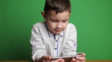 Akıllı telefon tutan sevimli çocuk ilginç bir şeye bakıyor..
