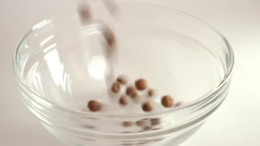 Granola beyaz arka planda şeffaf bir kaseye dökülüyor. Sağlıklı yemek..