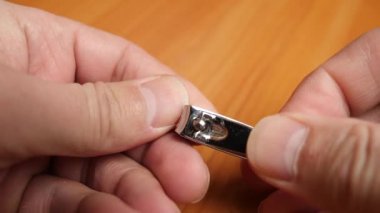 The man uses pliers to cut the nails on his fingers. Hand hygiene.