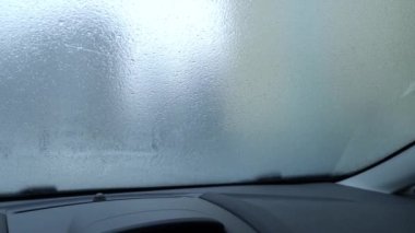 Frozen, icy car windshield. Use of the car in winter and during adverse weather conditions. Shooting from a car.