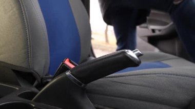 Adam arabaya biner, emniyet kemerini bağlar ve el frenini çeker. Güvenli araba kullanımı kavramı.