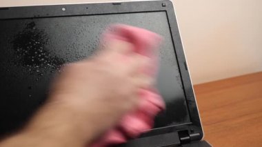 Adam dizüstü bilgisayarı deterjan ve bezle yıkıyor. PC bakım kavramı