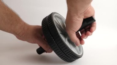 Bir adam spor egzersizleri yapmak için iki eliyle jimnastik tekerleği tutuyor..