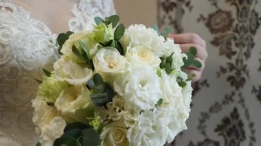 Gelin, güzel bir düğün buketini nazikçe yapraklarına dokunarak inceliyor.