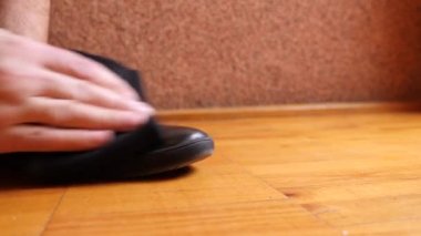 A man cleans leather shoes with a rag. Shoe care.