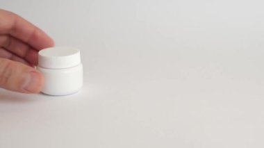 Adam plastik bir şişe açıyor ve koluna tıbbi kapsüller döküyor. Tıbbi aygıtların kullanımı.