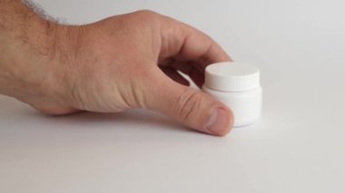 Adam plastik bir şişe açıyor ve koluna tıbbi kapsüller döküyor. Tıbbi aygıtların kullanımı.