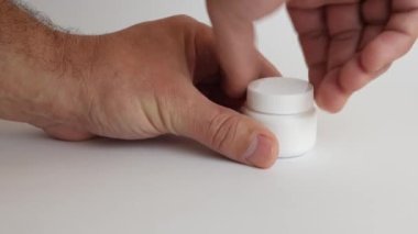 Adam plastik bir şişe açıyor ve koluna tıbbi kapsüller döküyor. Tıbbi aygıtların kullanımı.