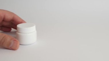 Adam plastik bir şişe açıyor ve koluna tıbbi kapsüller döküyor. Tıbbi aygıtların kullanımı.