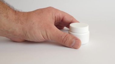 Adam plastik bir şişe açıyor ve koluna tıbbi kapsüller döküyor. Tıbbi aygıtların kullanımı.