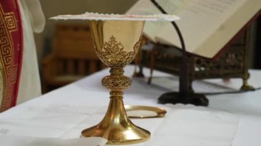 Rahip, günah çıkardıktan sonra ayin için hazırlanan altın kadeh için dua eder..