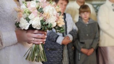 Gelin bir kilise düğününde güzel bir buket tutuyor..