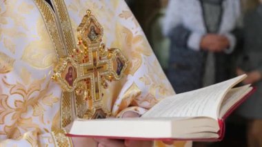 Rahip, ayin sırasında kilisenin kitabını okurken haçı tutuyor..