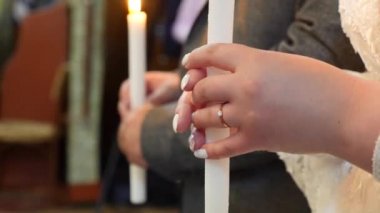 Gelin ve damat düğün sırasında ellerinde yanan mumlar tutuyorlar..