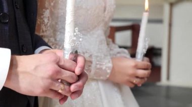 Gelin ve damat kilisenin düğününde mum tutuyorlar..