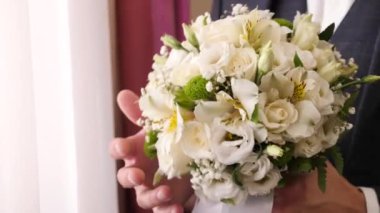 Adam ellerini tutuyor ve güzel bir buketi inceliyor..