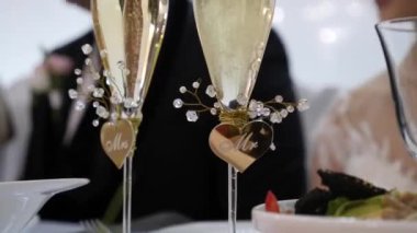 Üzerinde yazılar olan iki bardak, Bay ve Bayan beyaz, köpüklü şampanyayla dolu..