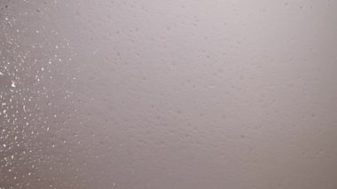 Renkli su damlaları camın üstüne düşer.