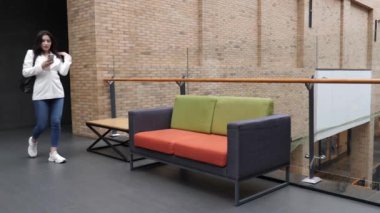 Güzel bir kız alışveriş merkezinde oturuyor ve akıllı bir telefonla konuşuyor..