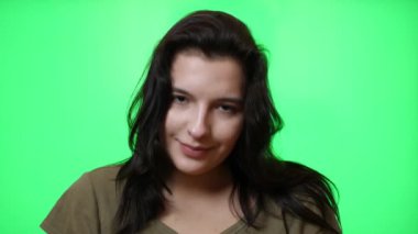 Yeşil arka planda güzel bir gülümsemesi olan güzel bir genç kız..