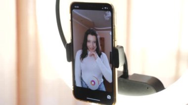 Girl blogger dances in a tick-talk style writing on a smartphone with a ring lig