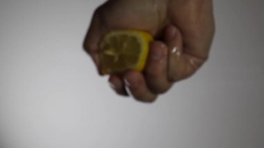 Adam bardağa limon suyu sıkıyor. Camın altından bak.