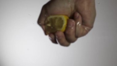 Adam bardağa limon suyu sıkıyor. Camın altından bak.