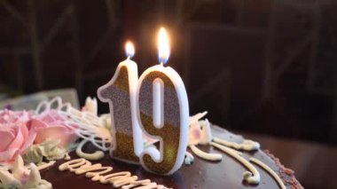 Adamın biri pastaya mum üflüyor. 19 numara şeklinde.