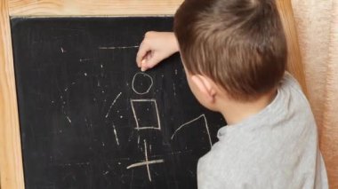 Evde öğreniyorum. Çocuk tahtaya tebeşirle yazmayı öğreniyor..