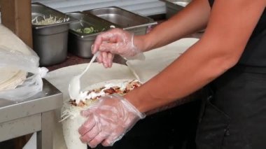 Şef içine sos ve ketçap ekleyerek birkaç porsiyon shawarma hazırlar. Sokak yemekleri konsepti.