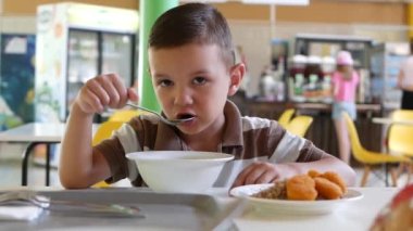 Yakışıklı bir çocuk yemek odasında bir masaya oturur ve doğrudan çocuk odasında iştah açıcı bir şekilde öğle yemeğini yer. Anında Çocuk Duyguları.