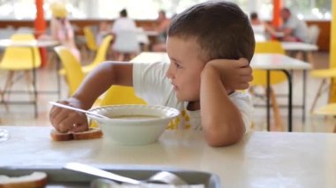 Yakışıklı bir çocuk yemek odasında bir masaya oturur ve doğrudan çocuk odasında iştah açıcı bir şekilde öğle yemeğini yer. Anında Çocuk Duyguları.
