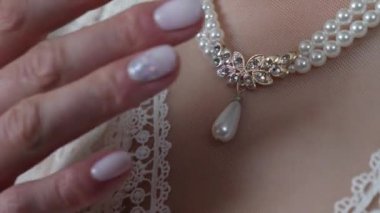 Woman puts jewelry on her neck. Preparing for the celebration.