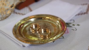 Wedding rings on a gold plate. Church wedding ceremony of brides.